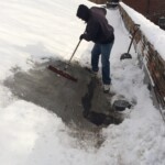 Roofing in winter Man sweeping snow from roof